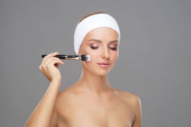 Güzellik makyaj fırçası ile genç ve çekici bir kadın portresi. Makyaj ve kozmetik kavramı.