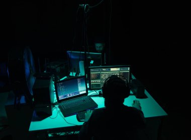 Aranan hackerlar virüs fidye yazılımını bodrumdaki bilgisayar ve dizüstü bilgisayarlarla kodluyorlar. Siber saldırı, sistem kırma ve kötü amaçlı yazılım kavramı.