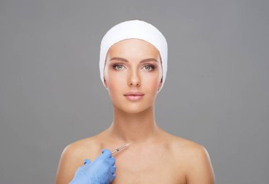 Genç bir kadının güzel yüzüne iğne yapan bir doktor. Estetik ameliyat, cilt gerdirme ve estetik tıp konsepti.