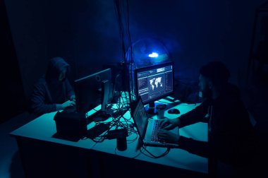 Aranan hackerlar virüs fidye yazılımını bodrumdaki bilgisayar ve dizüstü bilgisayarlarla kodluyorlar. Siber saldırı, sistem kırma ve kötü amaçlı yazılım kavramı.