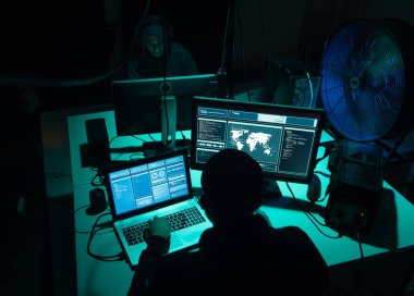 Aranan hackerlar virüs fidye yazılımını bodrumdaki bilgisayar ve dizüstü bilgisayarlarla kodluyorlar. Siber saldırı, sistem kırma ve kötü amaçlı yazılım kavramı.