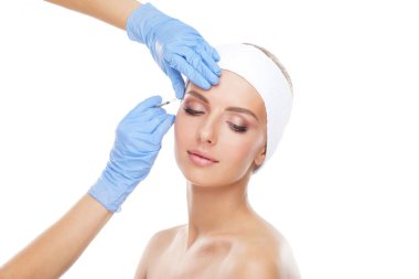 Genç bir kadının güzel yüzüne iğne yapan bir doktor. Estetik ameliyat, cilt gerdirme ve estetik tıp konsepti.