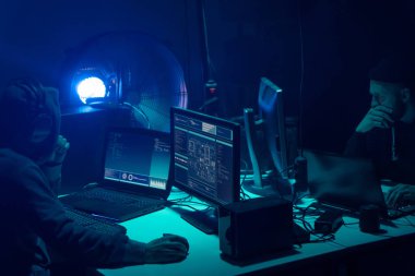 Aranan hackerlar virüs fidye yazılımını bodrumdaki bilgisayar ve dizüstü bilgisayarlarla kodluyorlar. Siber saldırı, sistem kırma ve kötü amaçlı yazılım kavramı.