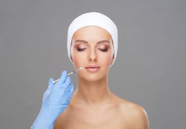 Genç bir kadının güzel yüzüne iğne yapan bir doktor. Estetik ameliyat, cilt gerdirme ve estetik tıp konsepti.