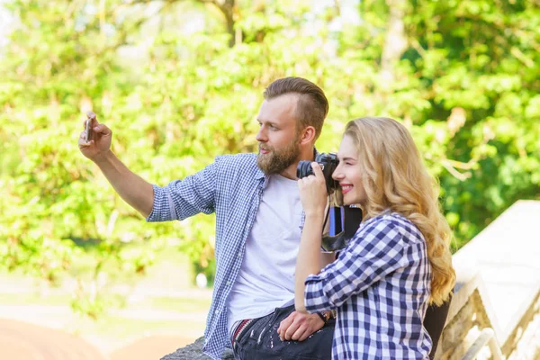 Homem e mulher tirando fotos com uma câmera e um smartphone . — Fotografia de Stock