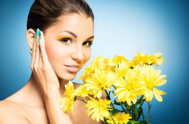 Güzel kadın ve mavi arka plan üzerinde sarı bir ayçiçeği portresi. Bahar kavramı.