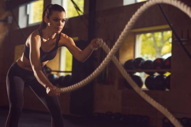 Bir spor salonunda çalışmaya uygun, sportif ve atletik sporcumuz. Savaş halatlar kullanarak Womantraining. Spor, atletizm, yaşam tarzı ve fitness kavramı.
