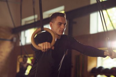 Formda, sportif ve atletik sporcu bir spor salonunda çalışıyor. Jimnastik halkalar kullanarak eğitim adam. Spor, atletizm, yaşam tarzı ve fitness kavramı.