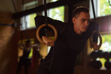 Formda, sportif ve atletik sporcu bir spor salonunda çalışıyor. Jimnastik halkalar kullanarak eğitim adam. Spor, atletizm, yaşam tarzı ve fitness kavramı.