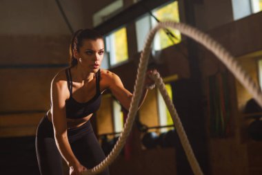 Bir spor salonunda çalışmaya uygun, sportif ve atletik sporcumuz. Savaş halatlar kullanarak Womantraining. Spor, atletizm, yaşam tarzı ve fitness kavramı.
