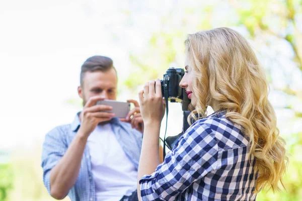 Homem e mulher tirando fotos com uma câmera e um smartphone . — Fotografia de Stock
