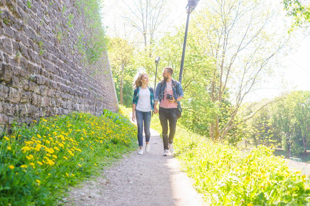 Young travelers walking in a park. Man and woman having vacation. Backpackers, traveling and tourism concept.