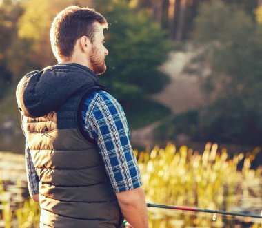Balıkçı bir iplik ve bir göl veya nehir üzerinde balık yakalamak yem ile. Adam bir balık tutma yolu ile bir hafta sonu. Hobi ve eğlence kavramı. Su ve Orman Doğa arka plan.