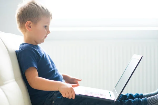 Portrait of happy boy playing with computer. Attractive kid with a laptop at home. Entertainment technology, futuristic gadgets and generation Z concept. — Stock Photo, Image