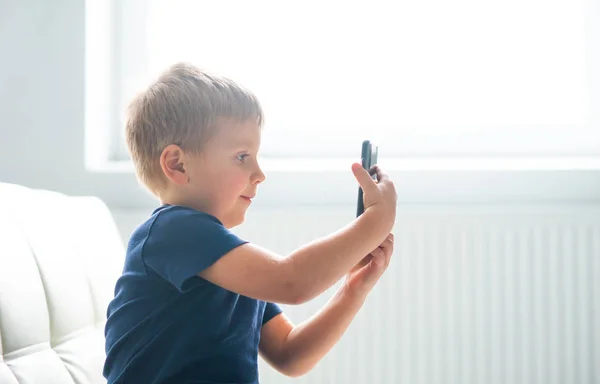 Portrait of happy boy playing with a smartphone. Kid with a mobile phone at home. Entertainment technology, futuristic gadgets, internet and generation Z concept. — Stock Photo, Image