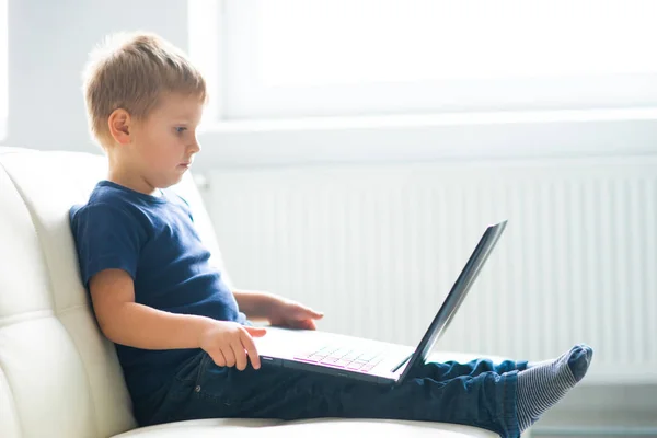 Portrait of happy boy playing with computer. Attractive kid with a laptop at home. Entertainment technology, futuristic gadgets and generation Z concept. — Stock Photo, Image