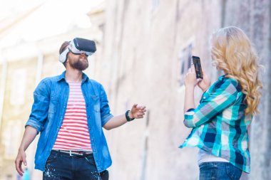 Artar veya sanal gerçeklik kulaklık sokakta yürüyen bir çift. VR, Ar, eğlence cihazları ve fütüristik teknoloji kavramı.