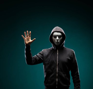 Bilgisayar korsanı beyaz maske ve kapüşonlu portresi. Gizlenmiş karanlık yüzü. Veri hırsız, internet dolandırıcılık, darknet ve siber güvenlik kavramı.