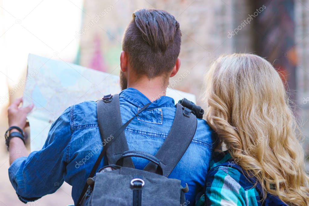 Young travelers exploring directions with a tourist map. Man and woman having vacation. Backpackers, traveling and tourism concept.