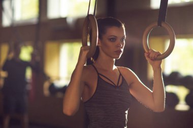 Bir spor salonunda çalışmaya uygun, sportif ve atletik sporcumuz. Jimnastik halkalar kullanarak eğitim kadın. Spor, yaşam tarzı, atletizm ve fitness kavramı.