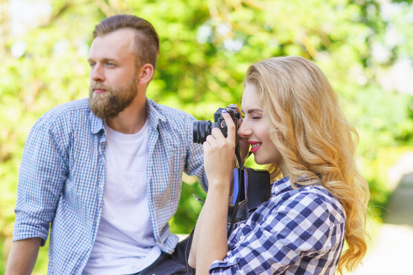 Man and woman having date outdoor. Girl wit a photo camera and her boyfriend. Couple in a park. Love, relations and traveling concept.