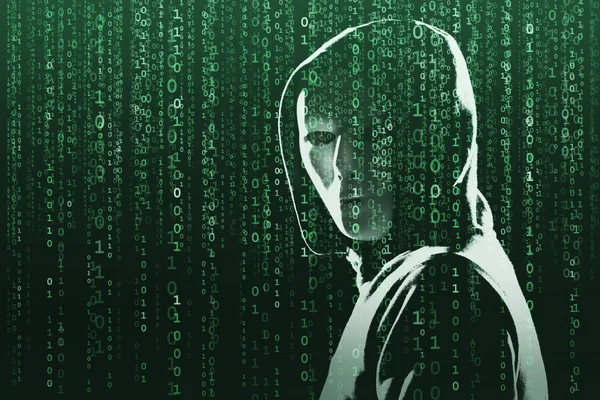 Anonymous computer hacker over abstract digital background. Obscured dark face in mask and hood. Data thief, internet attack, darknet fraud, dangerous viruses and cyber security concept.