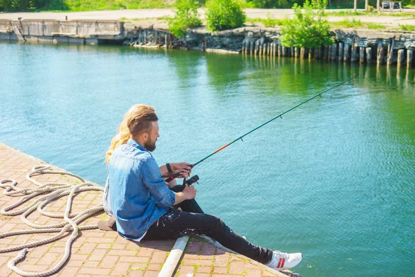 Man teaching his girlfriend to fishing. Couple with rod in harbor. Date, love and hobby concept.