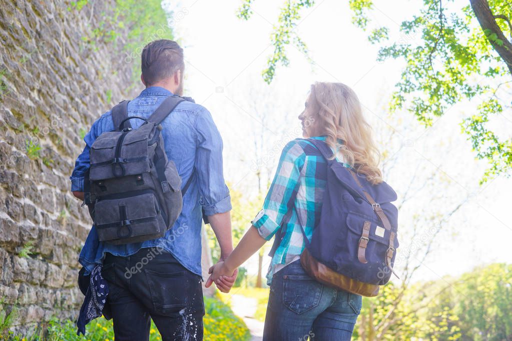 Young travelers walking in a park. Man and woman having vacation. Backpackers, traveling and tourism concept.