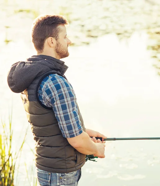 Balıkçı bir iplik ve bir göl veya nehir üzerinde balık yakalamak yem ile. Adam bir balık tutma yolu ile bir hafta sonu. Hobi ve eğlence kavramı. Su ve Orman Doğa arka plan.