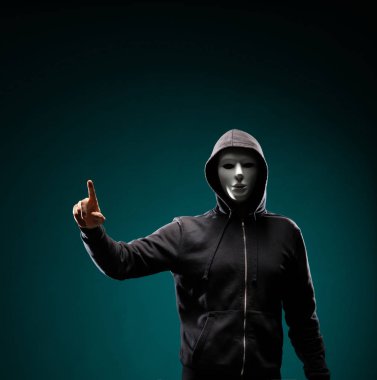 Bilgisayar korsanı beyaz maske ve kapüşonlu portresi. Gizlenmiş karanlık yüzü. Veri hırsız, internet dolandırıcılık, darknet ve siber güvenlik kavramı.
