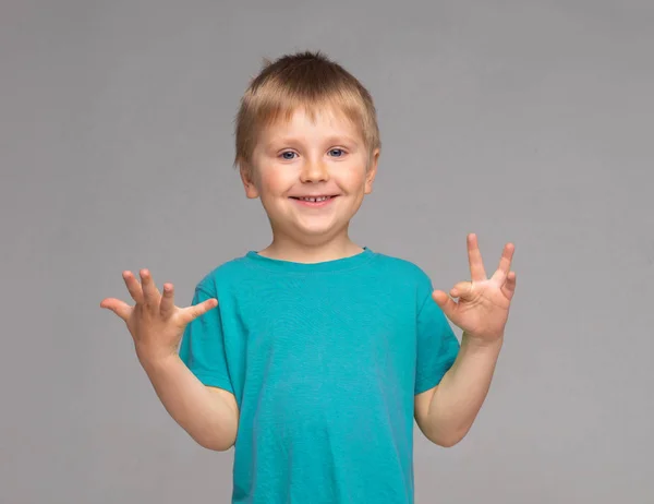 파란색 티셔츠를 입은 행복한 미소 짓는 소년의 초상화. 스튜디오에서 매력적인 아이. — 스톡 사진