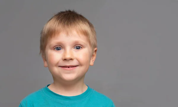 파란색 티셔츠를 입은 행복한 미소 짓는 소년의 초상화. 스튜디오에서 매력적인 아이. — 스톡 사진