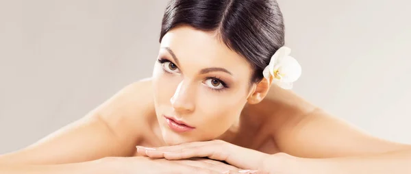 Mooie, jonge en gezonde vrouw in Spa Salon. Massage behandeling over grijze achtergrond. Spa, gezondheid en genezing. — Stockfoto