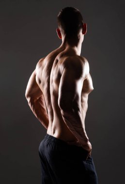 Siyah arka plan üzerinde güçlü, formda ve sporcu bir vücut geliştirici. Spor ve spor konsepti.