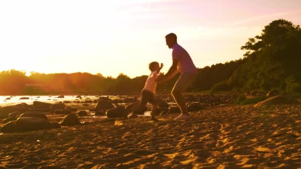 父は息子と海の近くで遊んでいる 日没や日の出の暖かい色 愛する両親と美しい子供たち 愛と父性と親子関係 — ストック動画