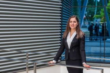 Modern ofis binasının önünde kendine güvenen bir iş kadını. İş, bankacılık, şirket, gayrimenkul ve finansal piyasa kavramı.