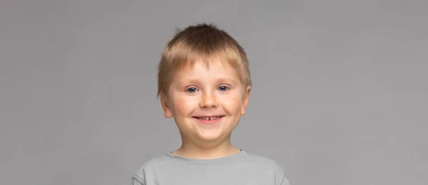 幸せな笑顔の少年の肖像画 灰色の背景の上にスタジオで魅力的な子供 — ストック写真