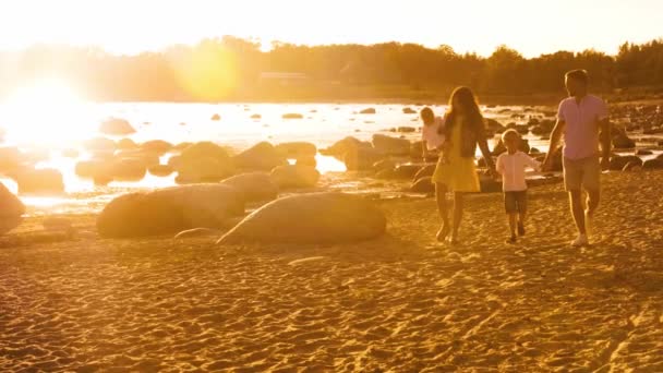 海の近くを歩く幸せな家族 ビーチと海日没や日の出の暖かい色 愛する両親と美しい子供たち 愛と親子の概念 — ストック動画