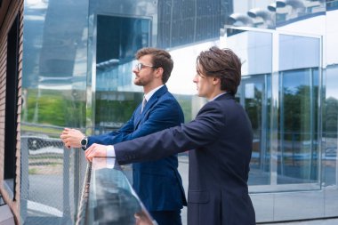 Kendine güvenen iş adamları modern ofis binasının önünde konuşuyorlar. İş adamı ve iş arkadaşı. Bankacılık ve finans piyasası kavramı.