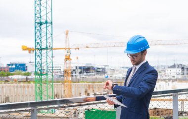 Kasklı emlak müteahhidi. Yeni ofis inşaatı. Modern ofis binası önünde kendine güvenen iş adamları veya mimar.