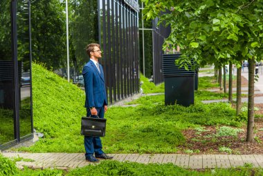 Modern ofis binasının önünde kendine güvenen bir iş adamı. Işadamı. Bankacılık ve finans piyasası kavramı.
