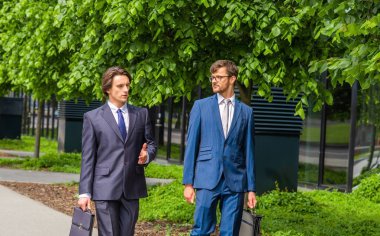 Kendine güvenen iş adamları modern ofis binasının önünde konuşuyorlar. İş adamı ve iş arkadaşı. Bankacılık ve finans piyasası kavramı.