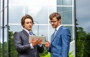 Kendine güvenen iş adamları modern ofis binasının önünde konuşuyorlar. İş adamı ve iş arkadaşı. Bankacılık ve finans piyasası kavramı.