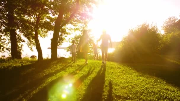 幸福的家庭在海边散步 乡间田地和树木 日落或日出的温暖颜色 慈爱的父母和美丽的孩子 爱和父母的概念 — 图库视频影像