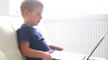 Bilgisayarla oynarken mutlu çocuk portresi. Çekici çocuk evde bir dizüstü bilgisayar ile. Eğlence teknoloji, fütüristik gadget'lar, internet ve nesil Z kavramı.