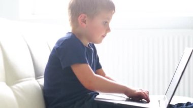 Bilgisayarla oynarken mutlu çocuk portresi. Çekici çocuk evde bir dizüstü bilgisayar ile. Eğlence teknoloji, fütüristik gadget'lar, internet ve nesil Z kavramı.