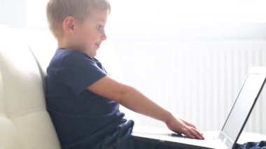 Bilgisayarla oynarken mutlu çocuk portresi. Çekici çocuk evde bir dizüstü bilgisayar ile. Eğlence teknoloji, fütüristik gadget'lar, internet ve nesil Z kavramı.