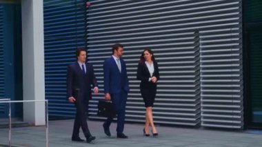Modern ofis binasının önünde konuşan emin işadamlarının. İşadamlarının ve iş kadınının işi var. Bankacılık, profesyonel iş ve finansal piyasa konsepti.
