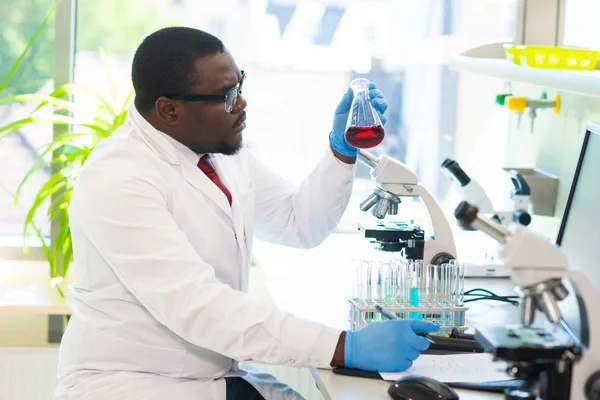 Афро-американський лікар працює в дослідницькій лабораторії. Науковий асистент, що робить фармацевтичні експерименти. Хімія, медицина, біохімії, біотехнології та охорони здоров'я. — стокове фото