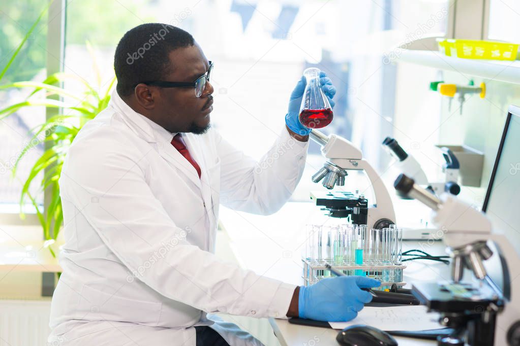 African-american medical doctor working in research lab. Science assistant making pharmaceutical experiments. Chemistry, medicine, biochemistry, biotechnology and healthcare concept.